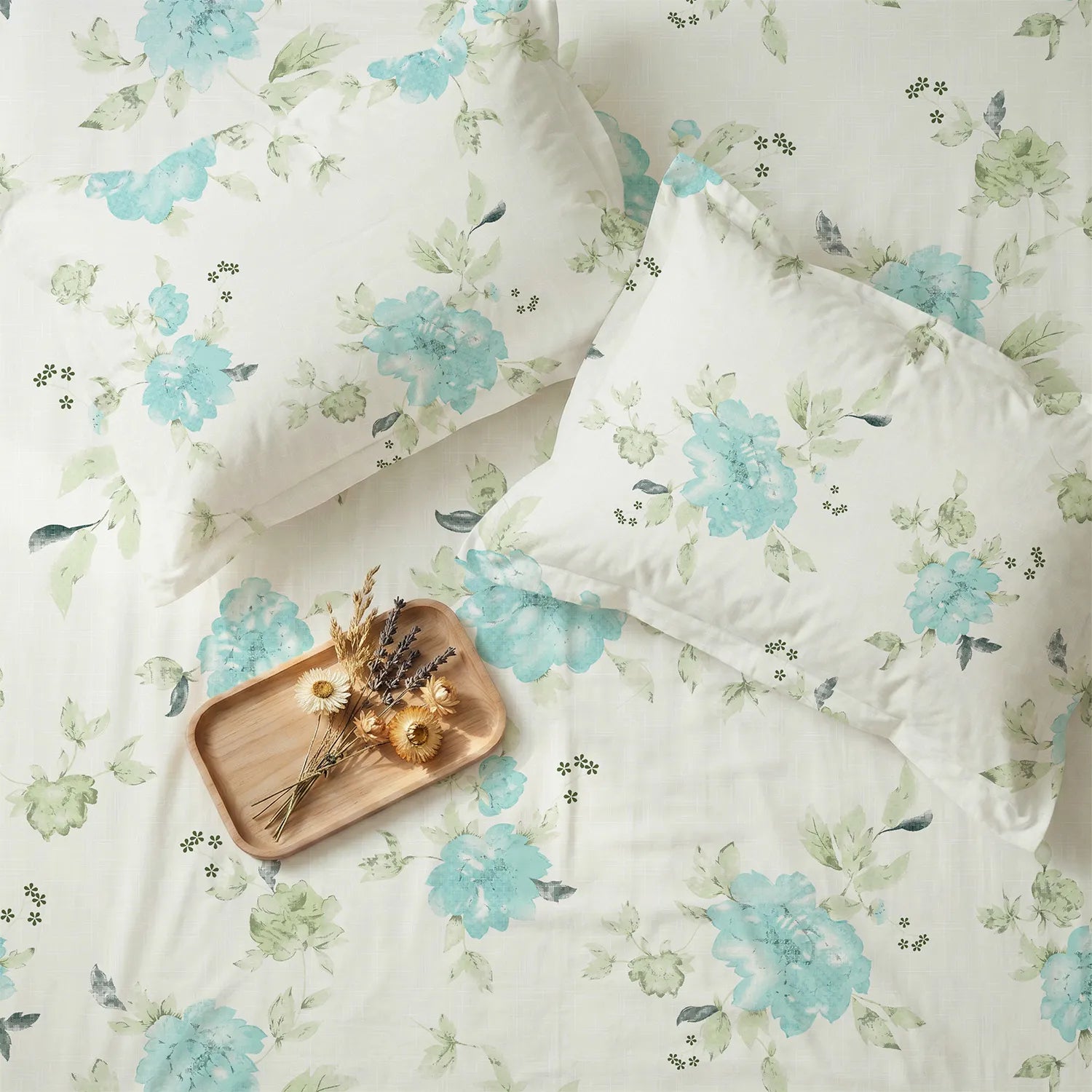 Floral bedding set with a wooden tray and dried flowers on a matching fabric background