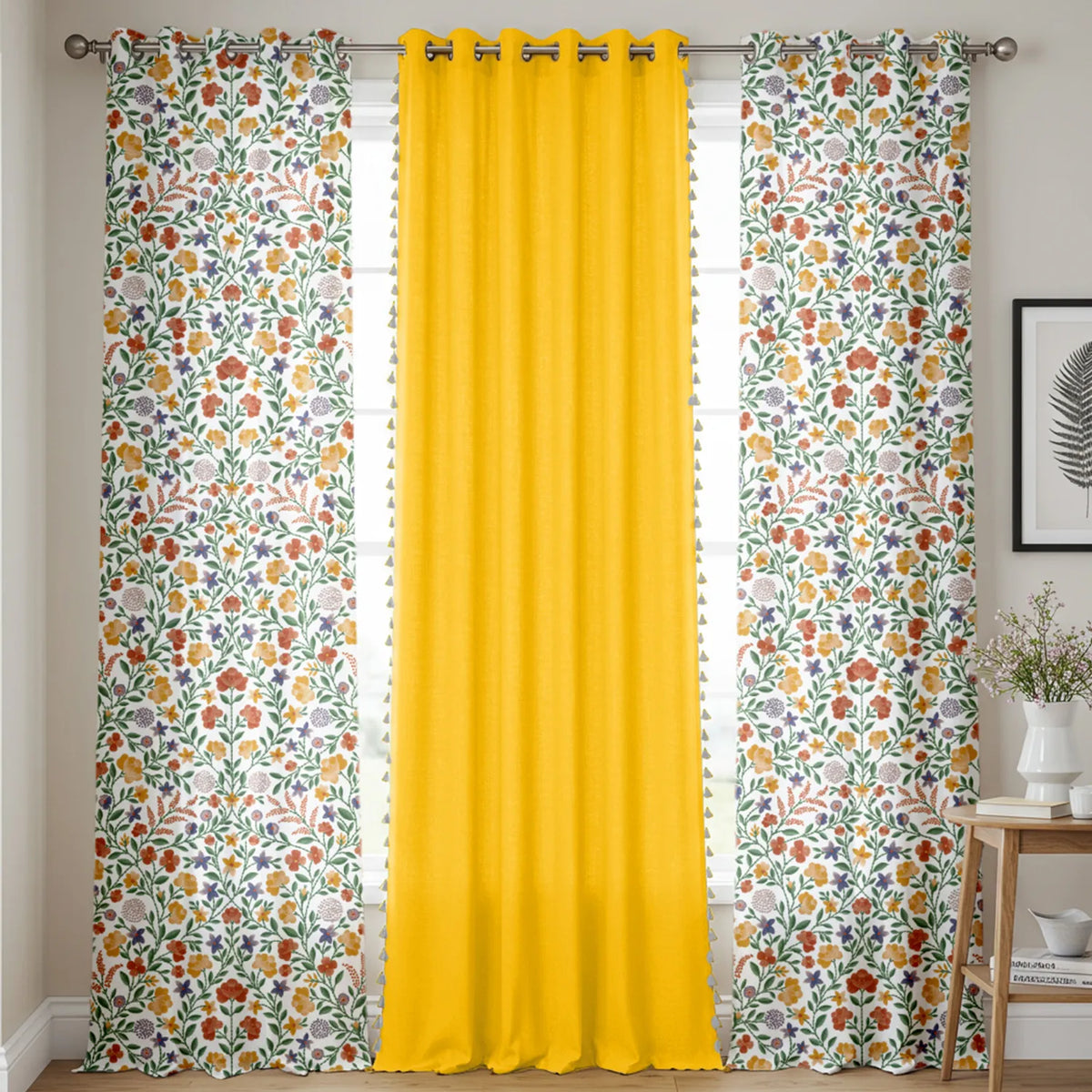 Set of three cotton curtains with two floral patterned panels in white, green, orange, and yellow, and one solid bright.